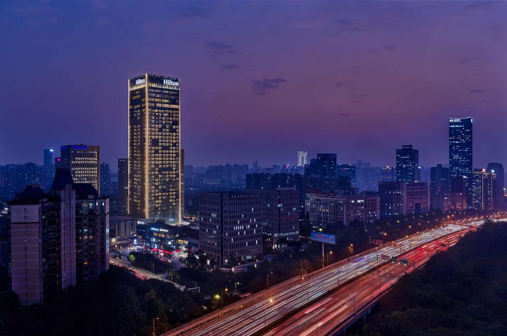 una città illuminata di notte con traffico in autostrada di Hilton Chongqing Liangjiang New Area a Chongqing