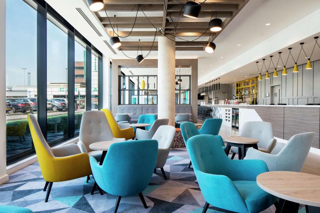 - une salle d'attente avec des tables, des chaises et des fenêtres dans l'établissement Hampton By Hilton Belfast City Centre, à Belfast