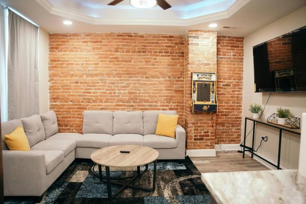 een woonkamer met een bank en een bakstenen muur bij Sleek and Cozy Micro Fells Point Residence! in Baltimore