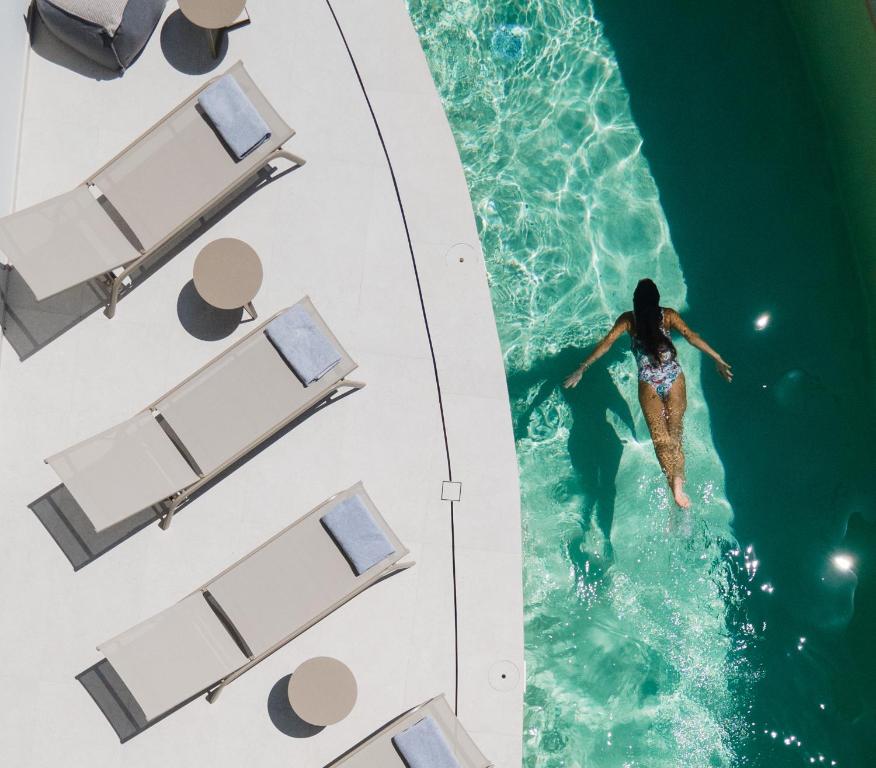 a woman is swimming in a swimming pool at Anapollo Boutique Hotel Adults Only in Naxos Chora