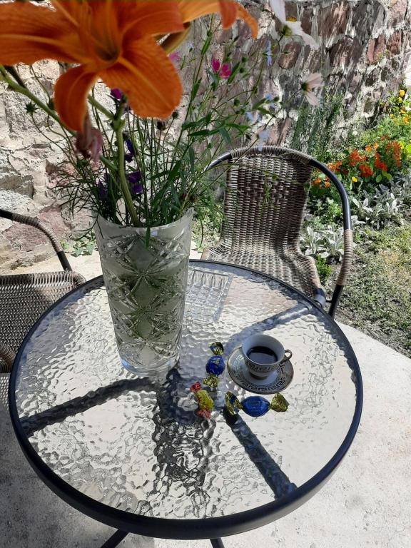 uma mesa de vidro com um vaso e flores sobre ela em Royal Galaxy apartment em Kazbegi