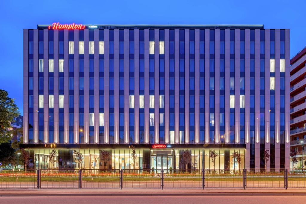 een hoog gebouw met blauwe ramen ervoor bij Hampton By Hilton Warsaw Mokotow in Warschau