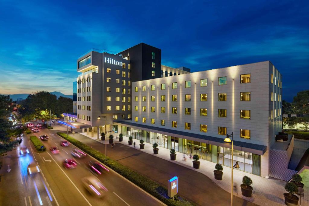 a building on a city street with cars on the road at Hilton Podgorica Crna Gora in Podgorica