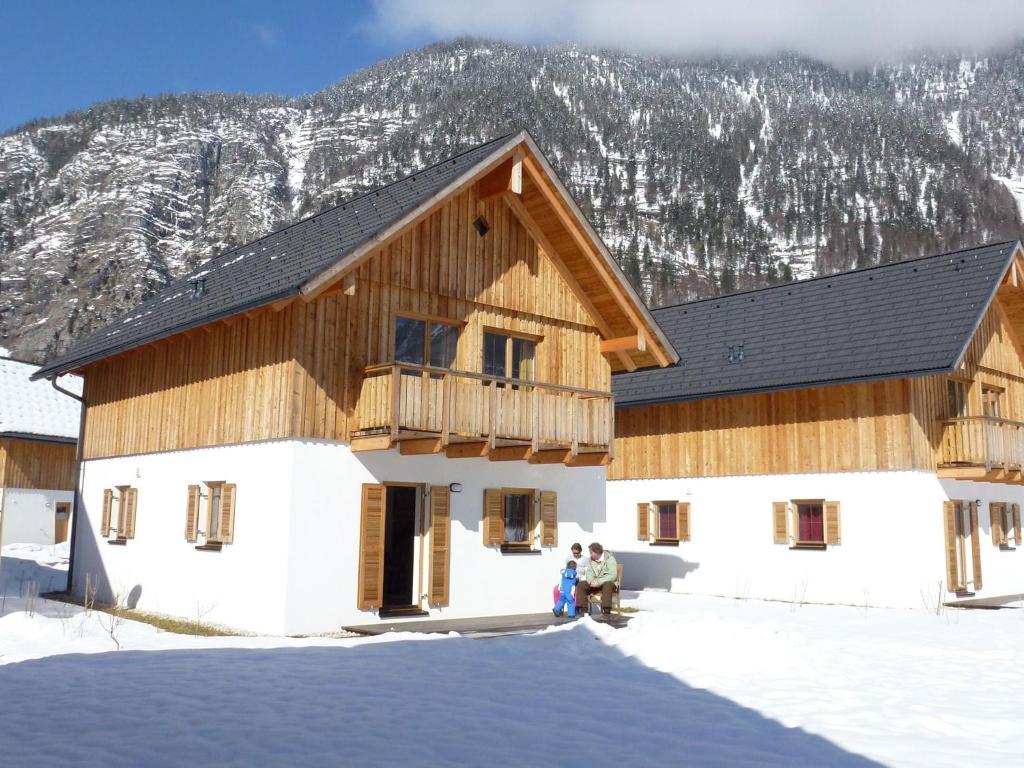 zwei Personen stehen vor einem Gebäude im Schnee in der Unterkunft Beautiful Chalet in Obertraun with Garden in Obertraun