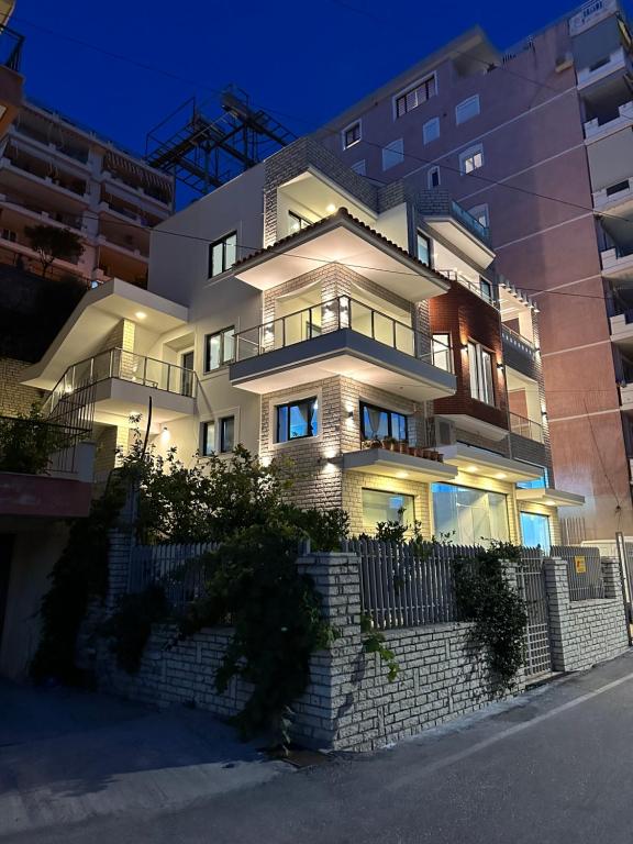 un gran edificio blanco con una valla delante en Villa Idrizi, en Sarandë