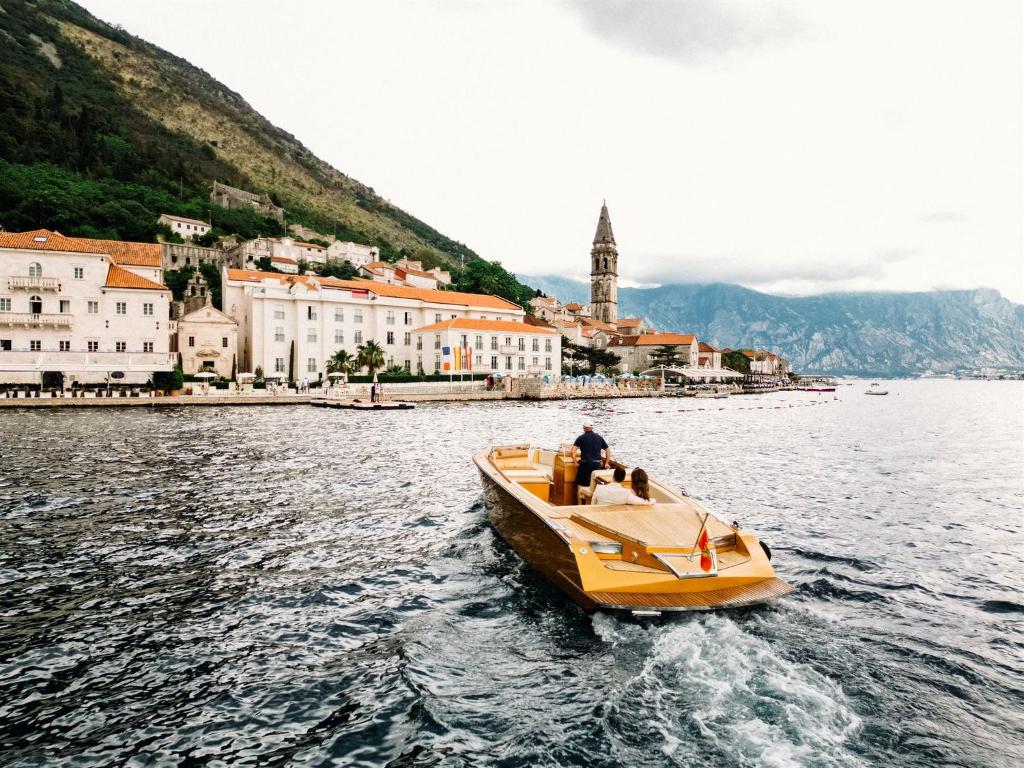 een man op een boot in het water bij een stad bij Heritage Grand Perast By Rixos in Perast