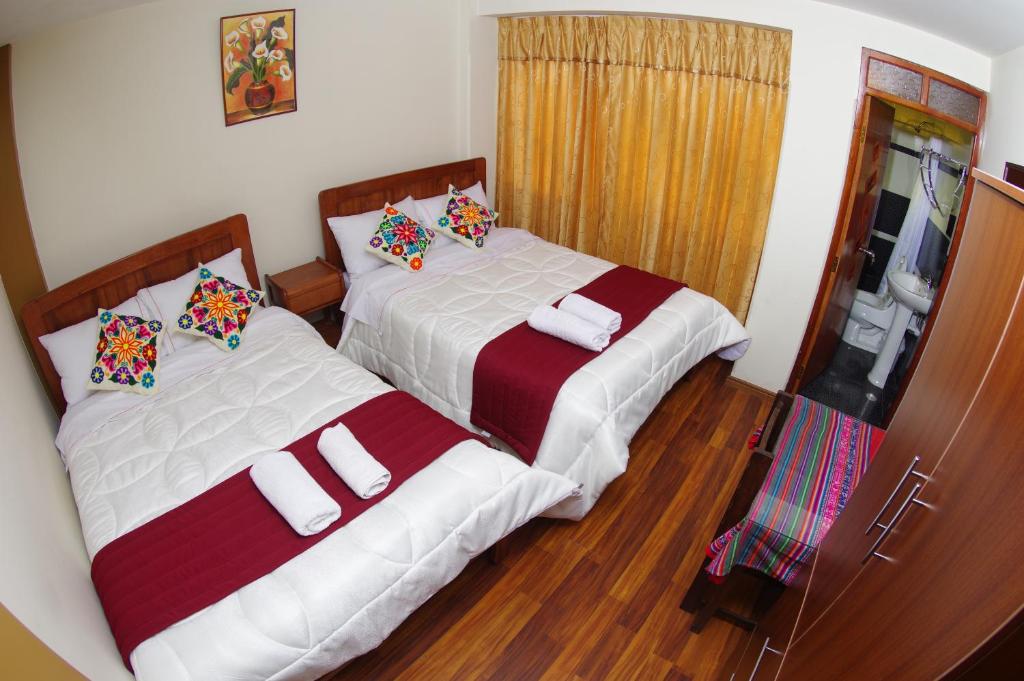 two beds sitting next to each other in a bedroom at Hostal Mirador Korichaska in Puno