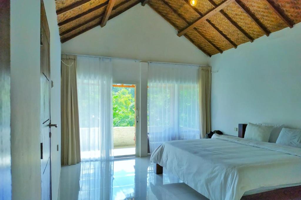 a bedroom with a bed and a large window at Hide and Seek in Tetebatu