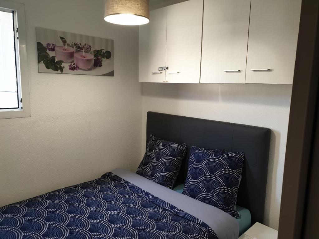 un letto con cuscini blu in una piccola stanza di Appartement vacances cap d’agde a Cap d'Agde