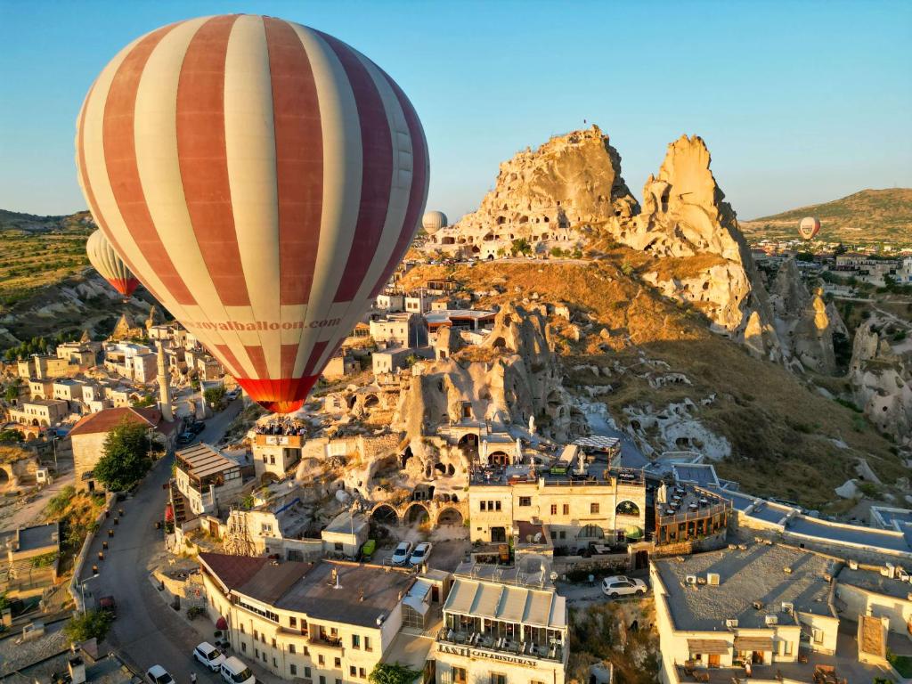 Ein Heißluftballon fliegt über eine Stadt in der Unterkunft Ages in Cappadocia in Uchisar