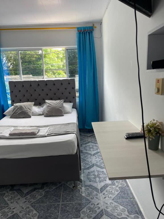 een slaapkamer met een bed met blauwe gordijnen en een tafel bij HospedajeLR in Barrancabermeja