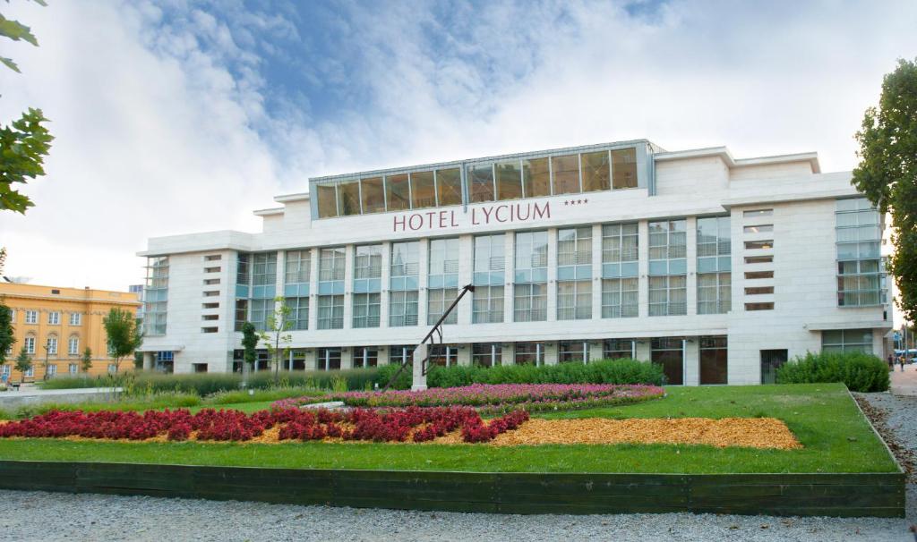 um hotel kyiv edifício com flores em frente em Hotel Lycium Debrecen em Debrecen