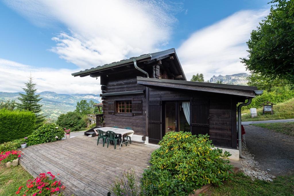 une cabane en rondins avec une table et des chaises sur une terrasse dans l'établissement Chalet du Brey - Avec terrasse et jardin, à Saint-Gervais-les-Bains