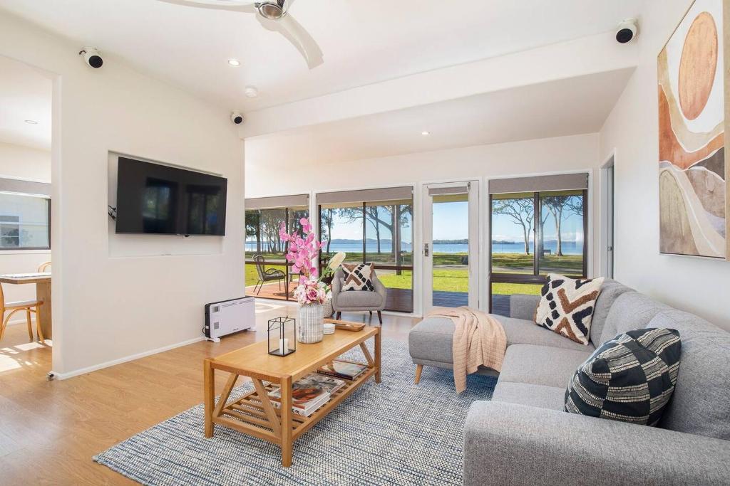 ein Wohnzimmer mit einem Sofa und einem Tisch in der Unterkunft 'Swan Cottage' Port Stephens Waterfront Solace in Newcastle