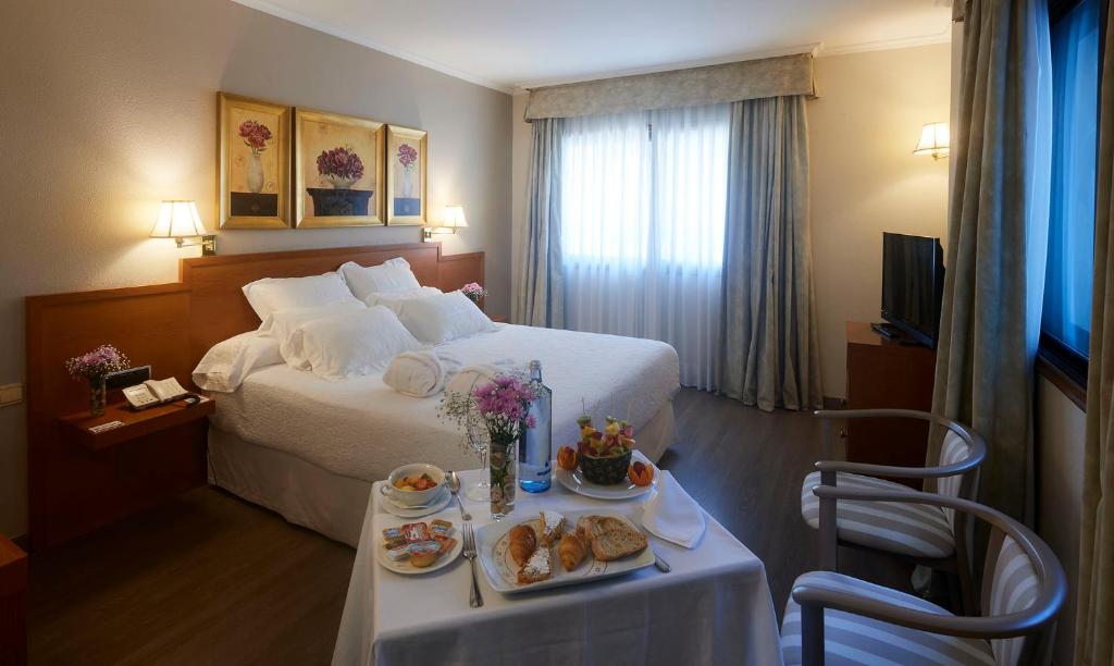 een hotelkamer met een bed en een tafel met eten erop bij Galicia Palace in Pontevedra