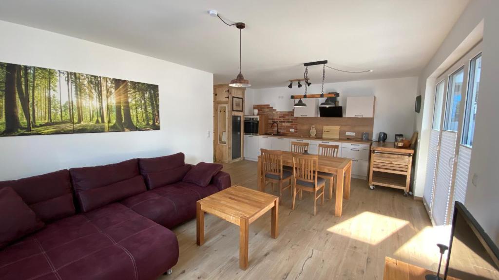 a living room with a couch and a table and a kitchen at Klönhüsing in Altefähr