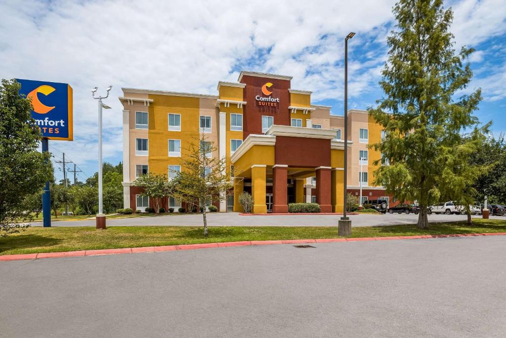 um grande edifício amarelo com um sinal em frente em Comfort Suites Denham Springs em Denham Springs