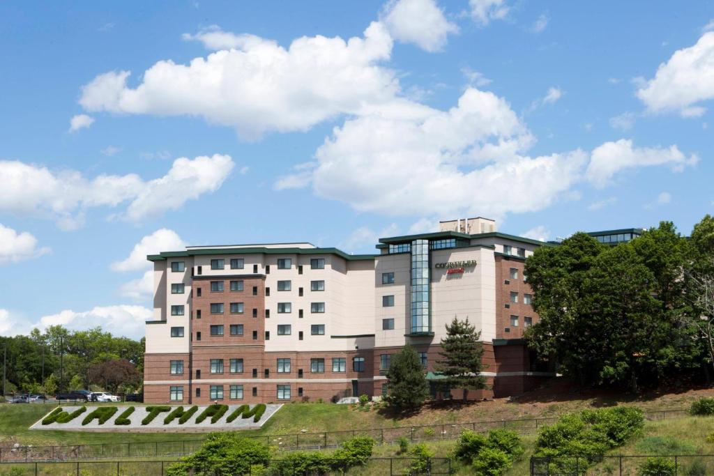 un bâtiment au sommet d'une colline plantée d'arbres dans l'établissement Courtyard by Marriott Boston Waltham, à Waltham