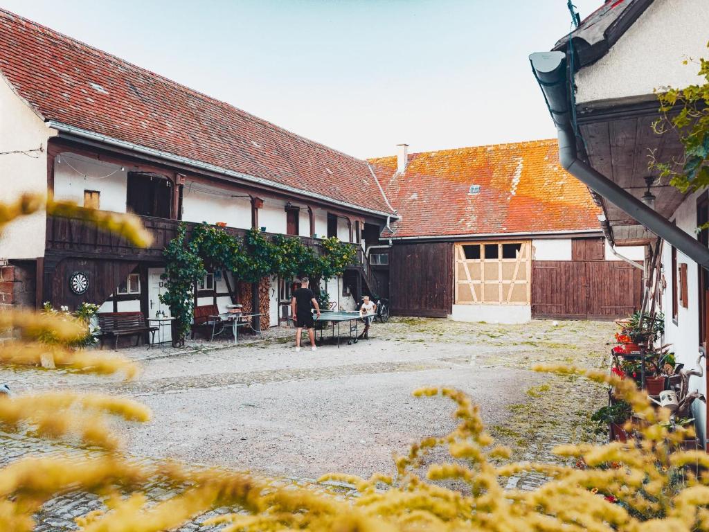 un groupe de bâtiments avec des personnes assises dans une cour dans l'établissement Ferienwohnung Brühler Hof, à Bad Berka