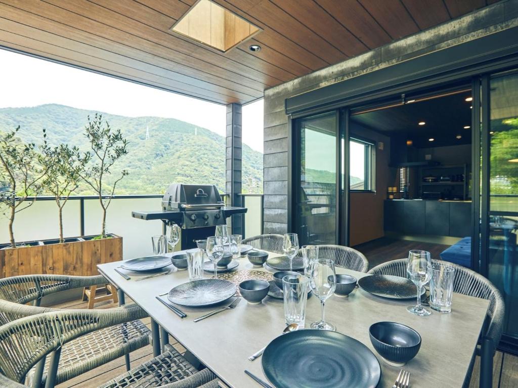 - une table avec des assiettes et des verres sur la terrasse dans l'établissement ルクス箱根湯本 LUX HAKONE YUMOTO, à Hakone