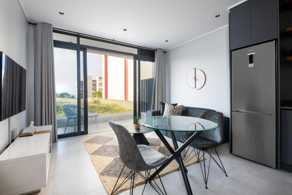 a kitchen with a glass table and chairs in a room at Luxury Bellagio 003 One Bed with Inverter in Durban