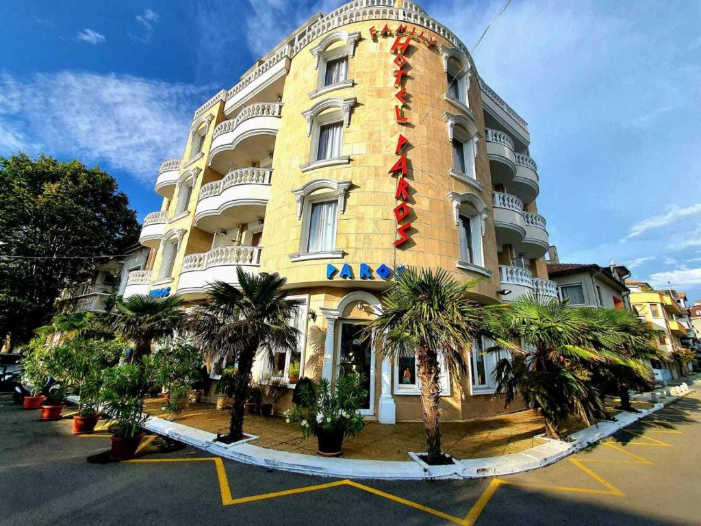 un grande edificio giallo con palme di fronte di Family Hotel Paros a Pomorie