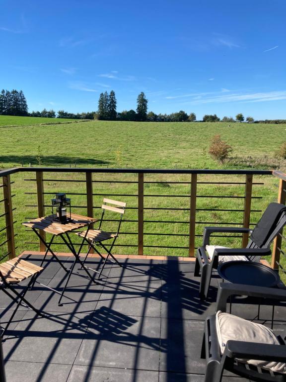 un patio con tavolo, sedie e campo di Au p'tit cachot (Gîte insolite) a Vaux-sur-Sûre