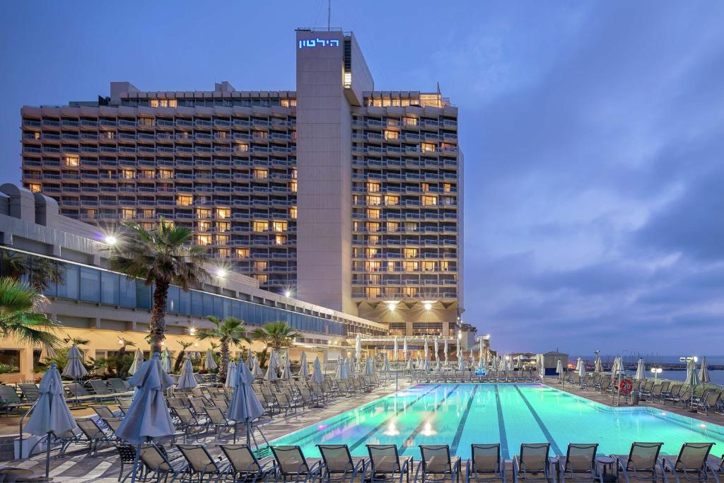 una gran piscina con sillas y un edificio en The Vista At Hilton Tel Aviv, en Tel Aviv