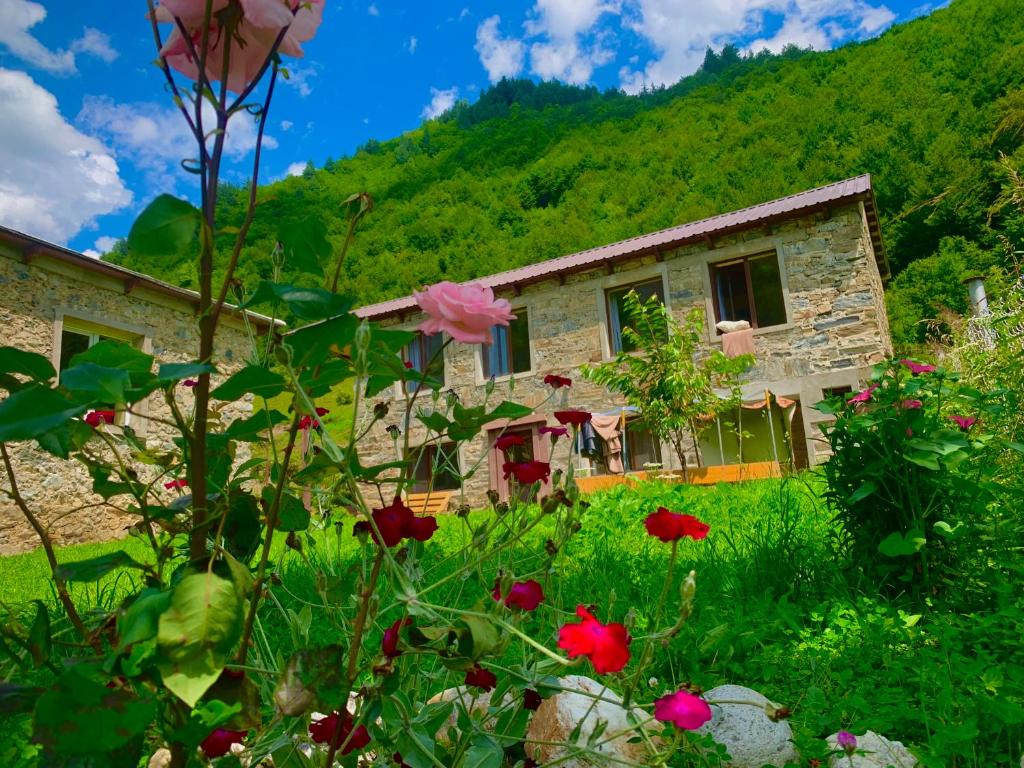 a stone house with flowers in front of it at River side SVANETI in Mestia