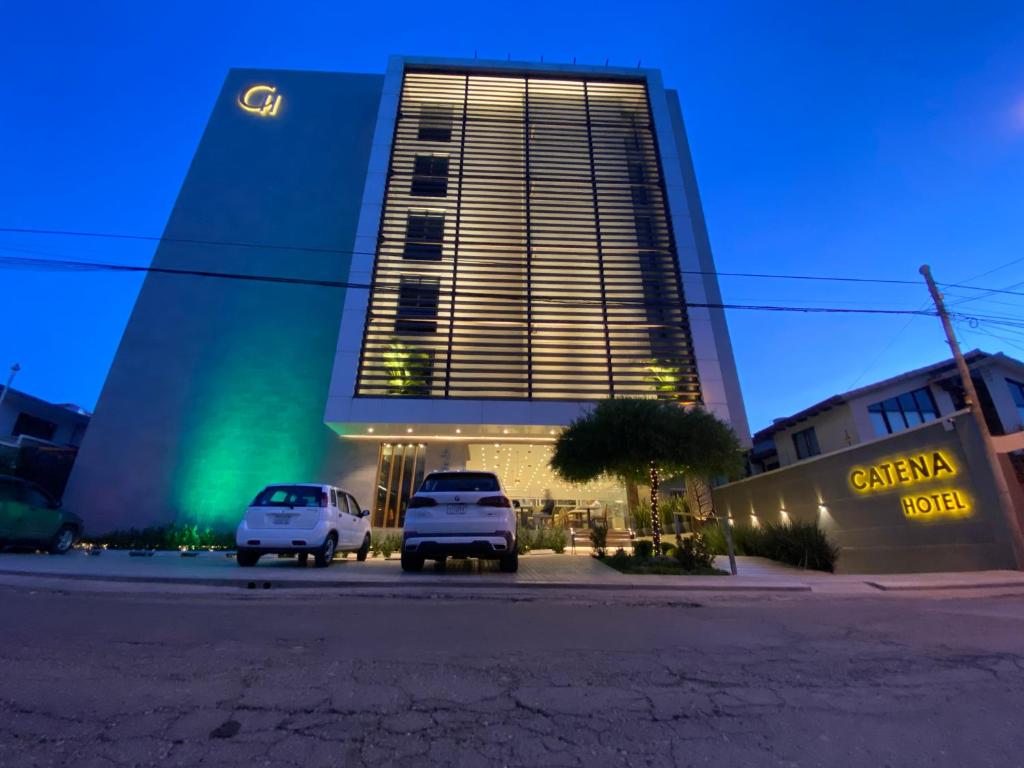 two cars parked in front of a building at night at Hotel Catena in Cochabamba