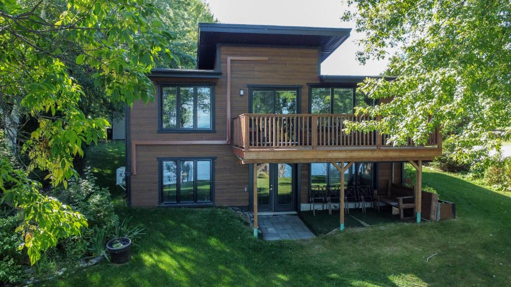 una casa con terraza en el césped en Magnifique chalet au bord du Lac-Saint-Jean, en Roberval