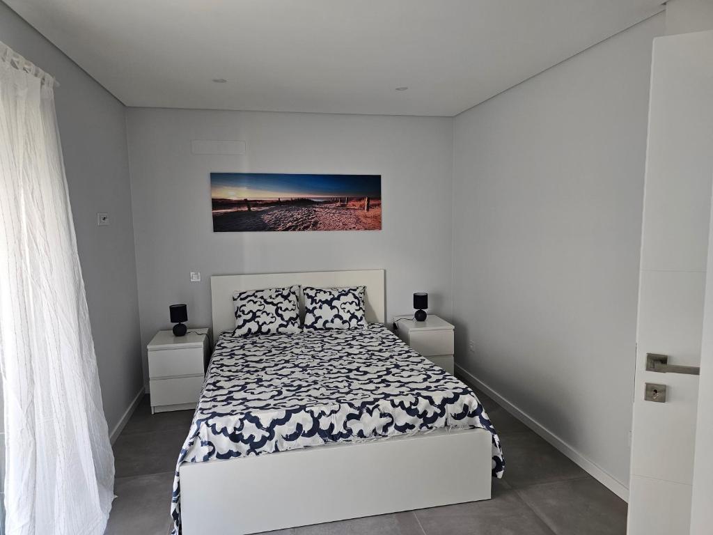 1 dormitorio blanco con 1 cama y una pintura en la pared en Apartment Dona Vitória - Monte Gordo Beach, en Monte Gordo