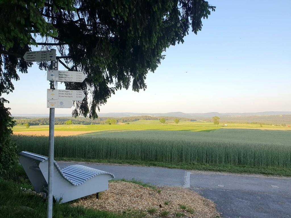 eine Bank neben einem Straßenschild vor einem Feld in der Unterkunft Ferienwohnung Naturpark Schwarzwald in Löffingen