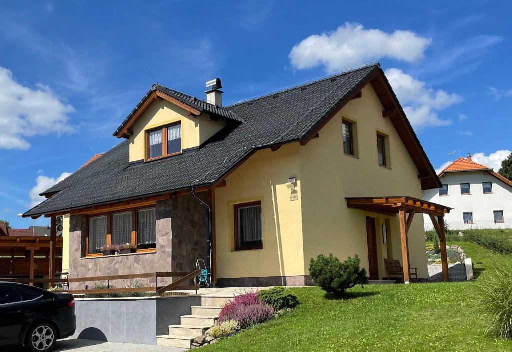 una casa gialla con tetto nero di Apartmán u Kovářů a Kašperské Hory