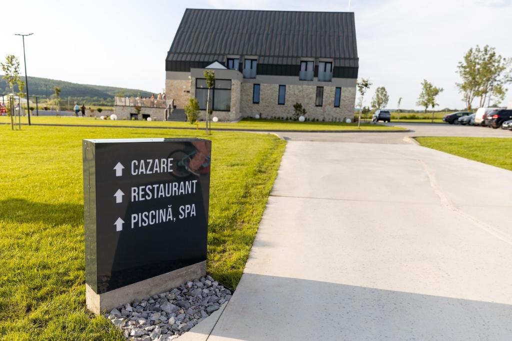 un panneau dans l'herbe avec un bâtiment en arrière-plan dans l'établissement Complex Acom, à Băile Felix