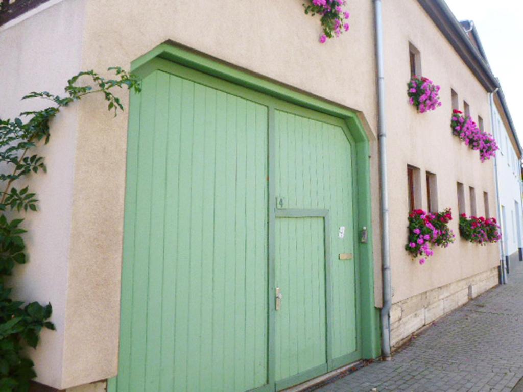 eine grüne Tür an der Seite eines Gebäudes mit Blumen in der Unterkunft Ferienwohnung Familie Mergner in Bad Langensalza