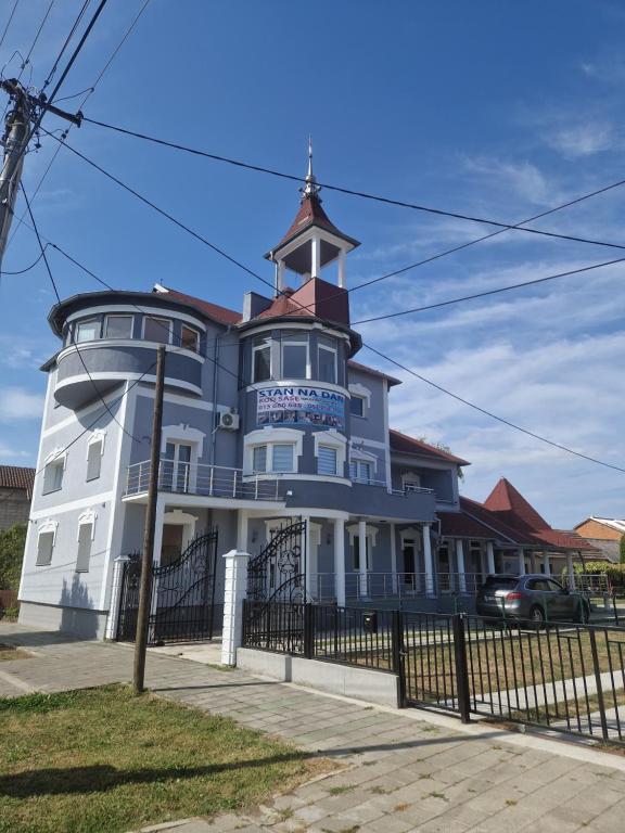 um edifício branco com uma torre de relógio no topo em Stan na dan kod sase em Bogatić