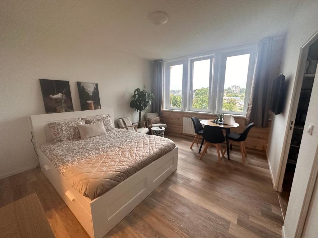 een slaapkamer met een bed en een tafel met stoelen bij Le Petit Port - La Belle Etoile in Sedan