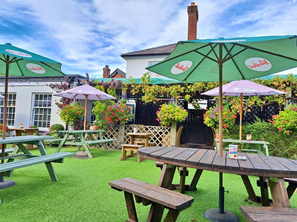 a picnic table with an umbrella on the grass at The Inn West End in Woking