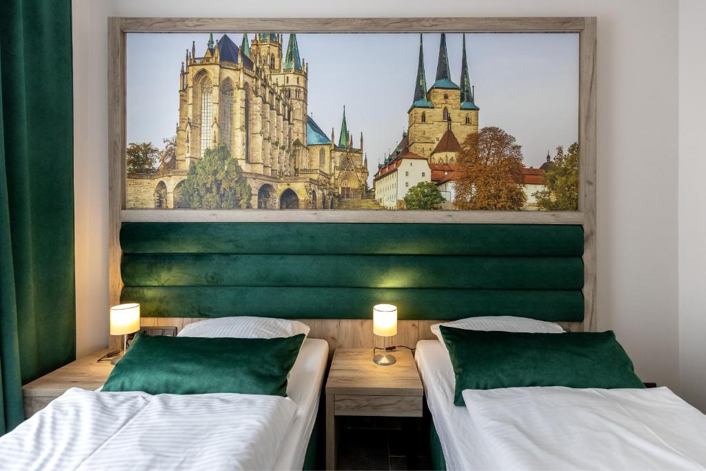 two beds in a room with a view of a castle at Hotel Garni " Am Domplatz" in Erfurt