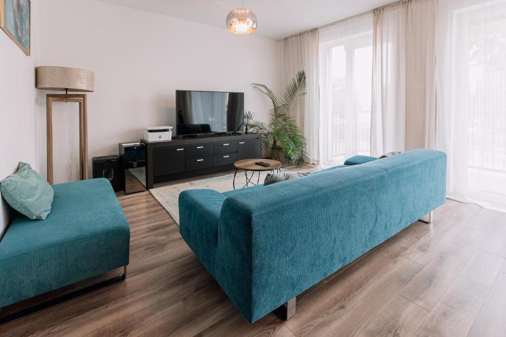 REVON Business apartment Senec في سينيتش: غرفة معيشة مع أريكة زرقاء وتلفزيون