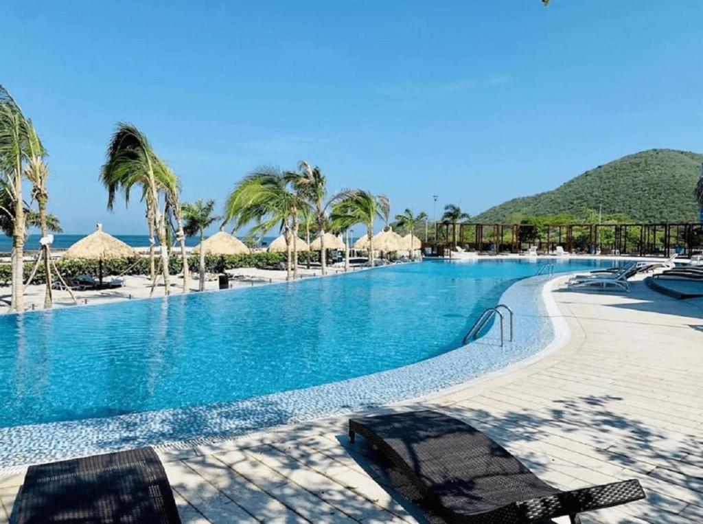 una piscina con sedie e ombrelloni su una spiaggia di Samaria Club de Playa - Pozos Colorados - By INMOBILIARIA VS a Santa Marta