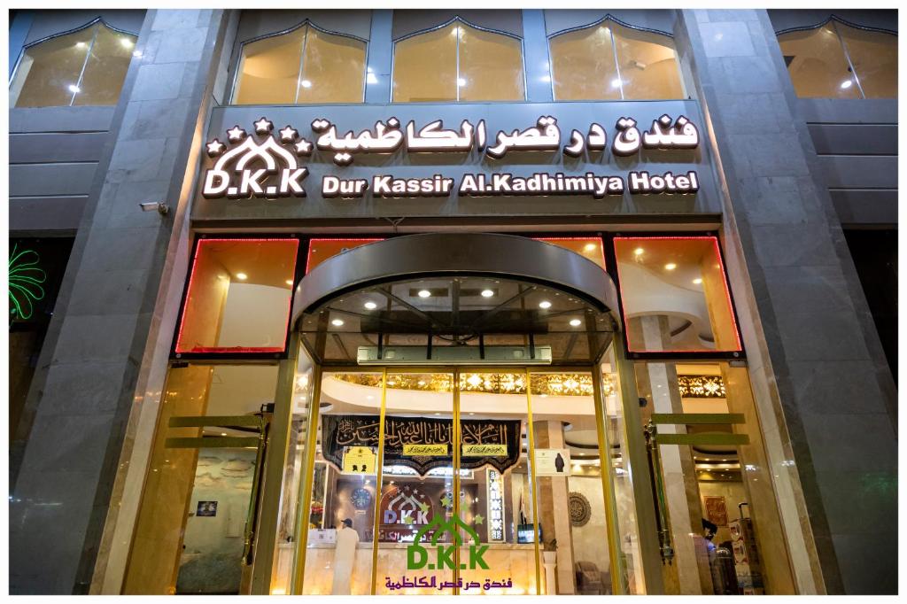 卡尔巴拉Dur Kassir Alkadhimiya Hotel的建筑物前面的商店,上面有标志