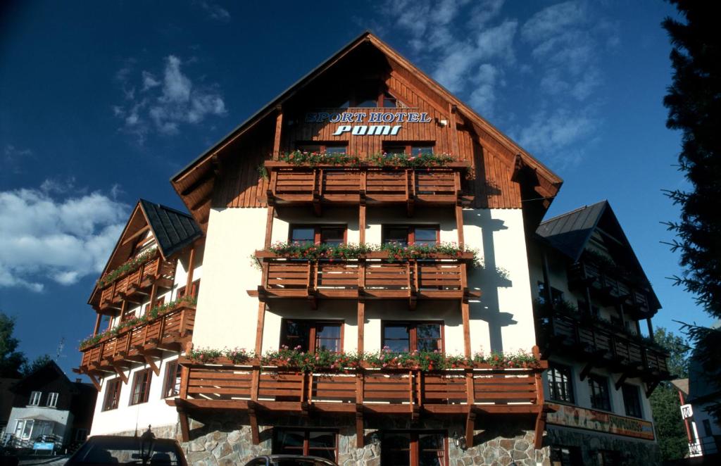 un edificio in legno con fioriere sopra di Sport hotel POMI a Harrachov