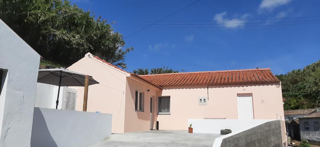 una casa bianca con un ombrello in un vialetto di Cantinho da Ribeira a Castelo Branco