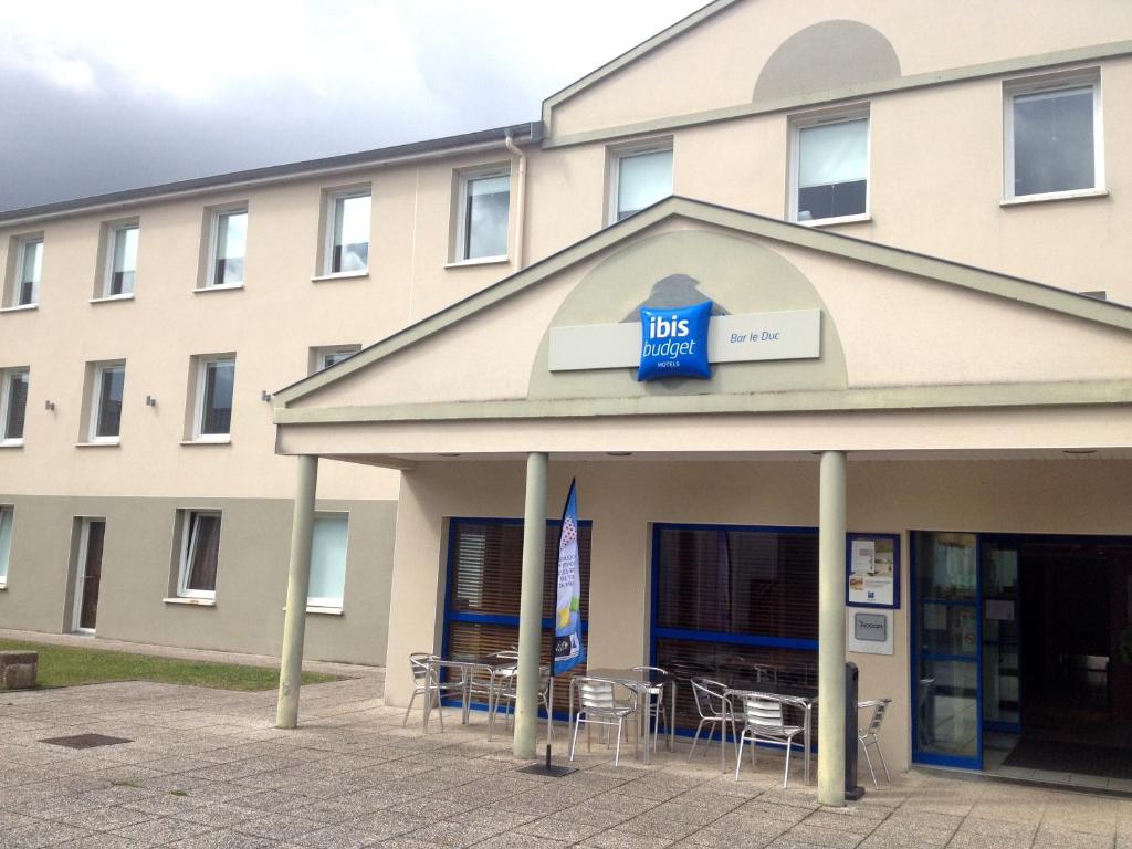 un bâtiment avec des tables et des chaises devant lui dans l'établissement ibis budget Bar le Duc, à Bar-le-Duc