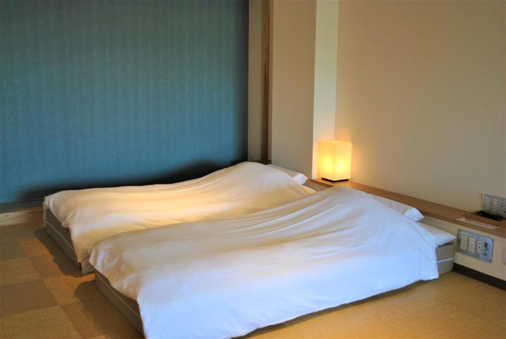 um quarto com uma cama branca e uma luz sobre ela em Kajitsu no mori - Vacation STAY 53781v em Ichinoseki