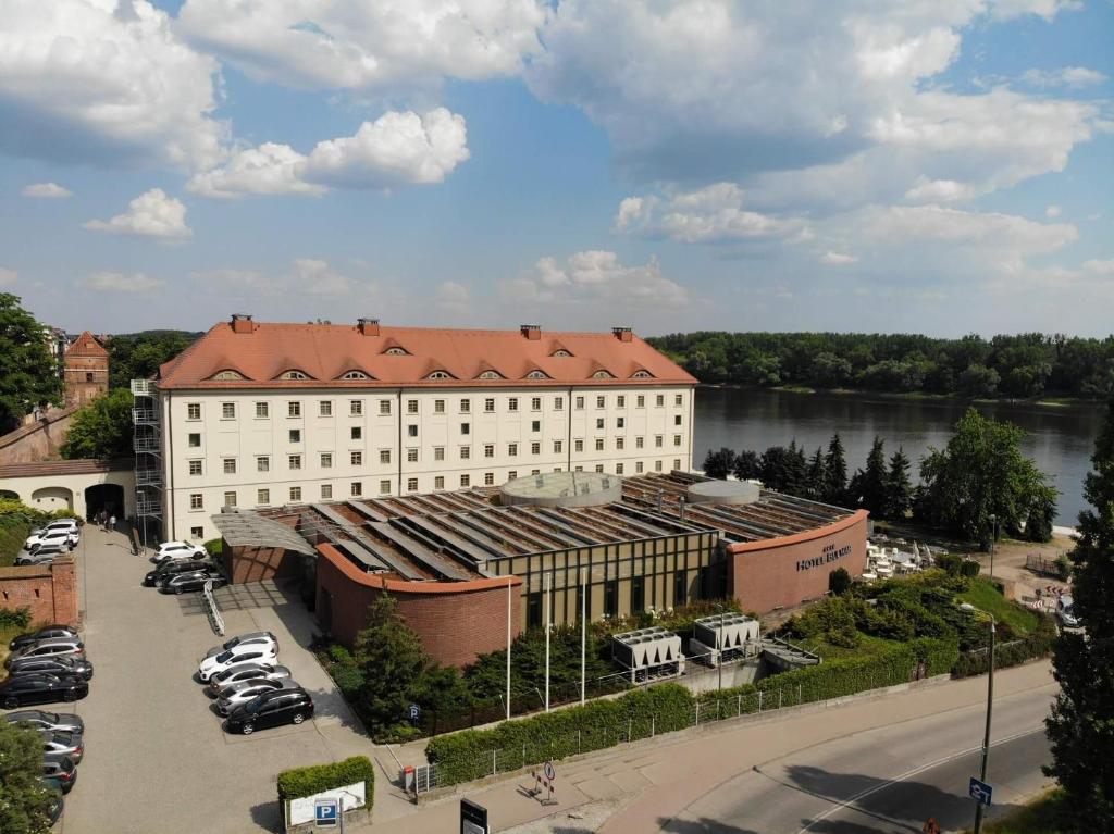 ein großes weißes Gebäude mit rotem Dach neben einem Fluss in der Unterkunft Hotel Bulwar in Toruń