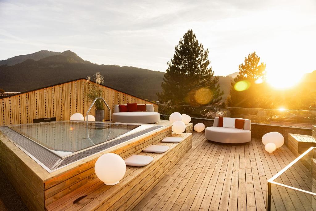 einen Whirlpool auf einer Holzterrasse mit Stühlen und Tischen in der Unterkunft Hotel Franks in Oberstdorf