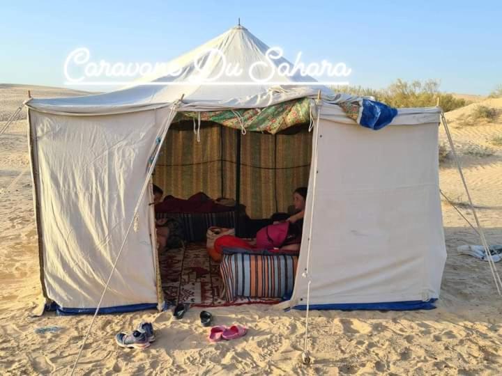 um homem sentado numa tenda na praia em Private Camp25km-from DOUZ em Douz